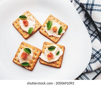 closed up on cream cracker biscuit with tomato and basil mionese on a white plate - Powered by Shutterstock