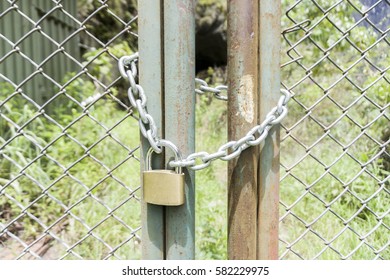 A closed padlock on the door of a metal gate