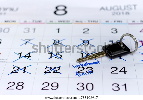 Closed up picture of car key on the white\
calendar with made marked on a date to mark appointment reminder of\
installment payments for car\
finance.