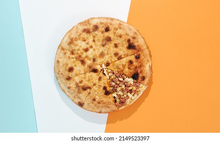 Closed pizza with minced meat, potatoes and cheese on coloured background. Meat pie with potatoes and cheese in minimal style. American pizza delivery concept with color backdrop - Shutterstock ID 2149523397