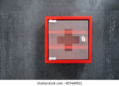 Closed Red Metal Empty Medicine Cabinet Hanging On A Dark Gray Marble Wall Background. Front View