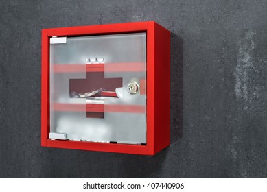 Closed Red Metal Medicine Cabinet Full Of Drugs Hanging On A Dark Gray Marble Wall Background. Perspective View