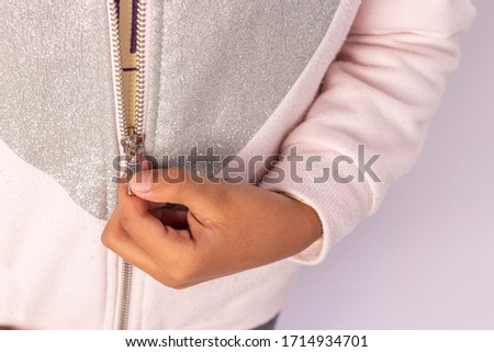 Closed shot of a hand pulling up the closure of a sweater