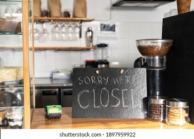 Closed Sign Board On The Bar Counter In An Empty Coffee Shop. Cafe, Bar Closed Due Outbreak Lockdown. Small Business Crisis Concept