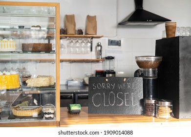 Closed Sign Board On The Bar Counter In An Empty Coffee Shop. Cafe, Bar Closed Due Outbreak Lockdown. Small Business Crisis Concept