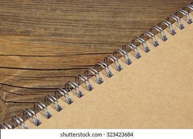 Closed Spiral Bound Notebook With Brown Paper Cover On Wood Rough Rustic Table Background Texture, Top View