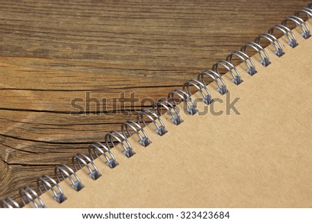 Closed Spiral Bound Notebook With Brown Paper Cover On Wood Rough Rustic Table Background Texture, Top View