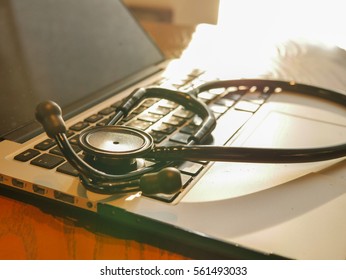 Closed Up Stethoscope On Laptop With Warm Light On Doctor Table