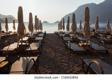 Closed sunshades on an empty beach early in the morning. Empty sunbeds. Beach without people. Beach at dawn  - Shutterstock ID 1760410856