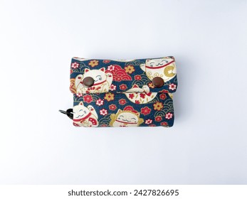 Closed thick wallet with dark blue and light brown fabric material and japanese neko cat design object isolated on horizontal white background. Big wallet for traveling with cute design.