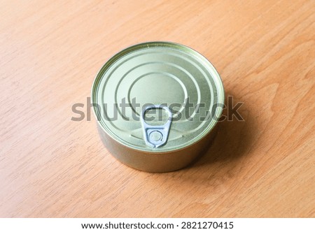 Closed tin can with pull ring easy open lid on wooden table back