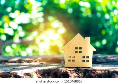 Closed Up Tiny Home Model On Floor Or Wood Board With Sunlight Green Bokeh Background. Deam Life Have Own House Property For Living Or Investment Concept.