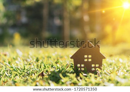 Closed up tiny home model on green grass with sunlight background.