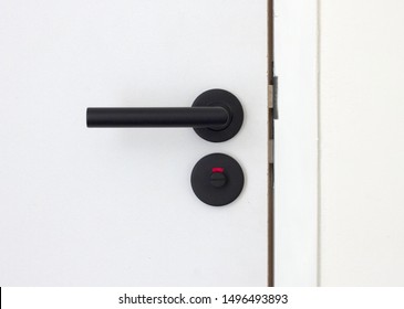 Closed toilet door, modern black handle, white door