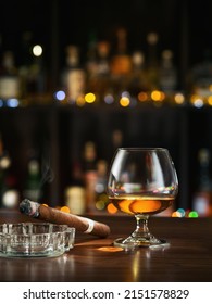 Closed up view of glass of cognac with cigar on color back