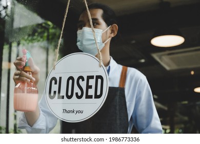 Closed. vintage sign board hanging on glass door with waitress staff wearing protective face mask cleaning and washing mirror window in cafe coffee shop restaurant, small business owner concept - Shutterstock ID 1986773336