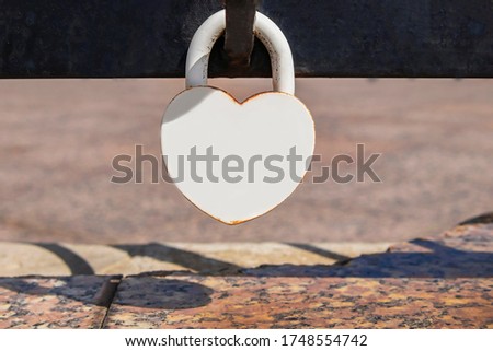 Closed white lock in the form of a heart. Due to weather conditions, the castle begins to rust, the paint cracks and collapses. Stockfoto © 