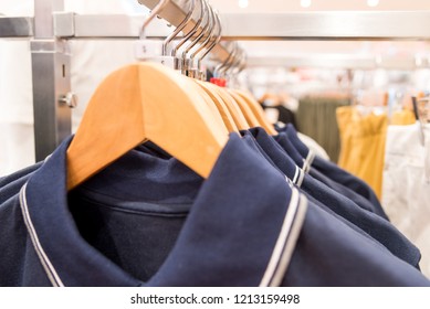 Closed up white and navy blue Mens  polo shirts on hangers and shelves in a retail clothes store