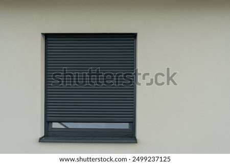 Closed window with roller shutter on white wall. Concept of security, privacy, and modern architecture. Metal sliding roller shutters for windows. High quality photo