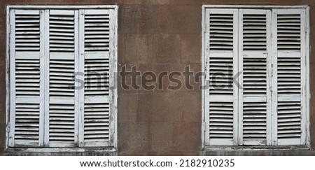 Closed windows. Window of a house closed with white wooden shutters. Old, ancient wood window with blind or shutters. stone home facade.