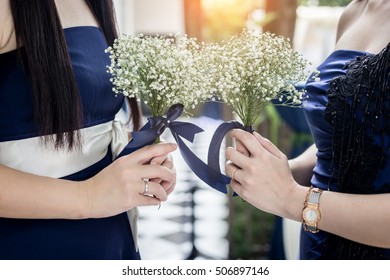 closed up woman's hand hold tiny beautiful white flower in dark blue dress with garden background