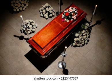 closed wooden coffin with candles and flowers in a dark and gloomy environment