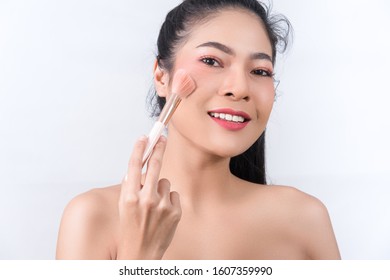 closed-up of Asian woman blushing her face with cosmetic on white background - Shutterstock ID 1607359990