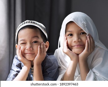 Closed-up Shot Of Asian Muslim Kids. A Young Sister And Brother Sibling In Muslim Traditional Dress.Happy And Looking To The Camera.Concept Of A Happy Kid In Ramadan Or Family Bonding.