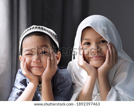 Closed-up shot of Asian Muslim kids. a young sister and brother sibling in Muslim traditional dress.Happy and looking to the camera.Concept of a happy kid in Ramadan or family bonding.