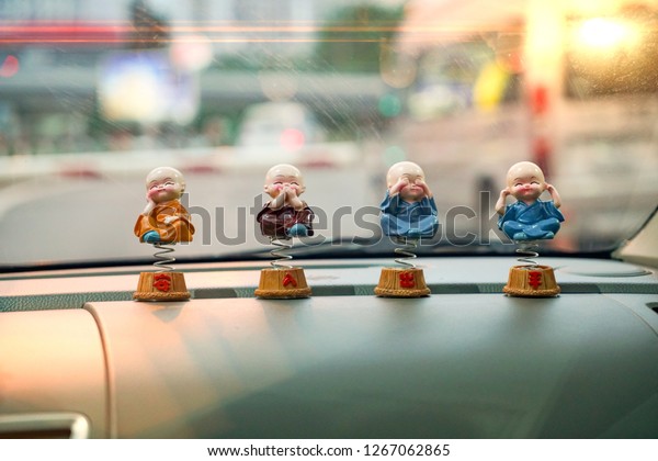 Close-focus of four young Kung Fu buddhist\
boys figure for car dashboard interior decoration. Chinese text\
means Happy , No Speak , No See , No Listen\
