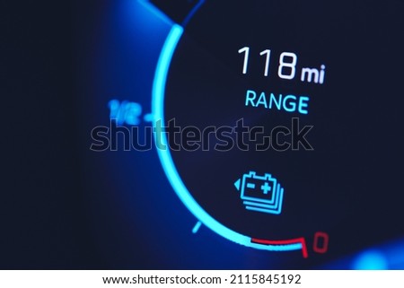 Close-in shot of electric car battery range gauge in blue