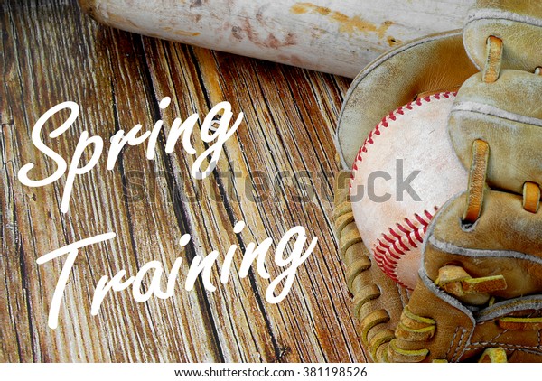 Closely\
cropped image of old, worn baseball equipment on a wooden\
background including a bat, mitt and ball. Spring training message\
added in white cursive text. Horizontal\
image.