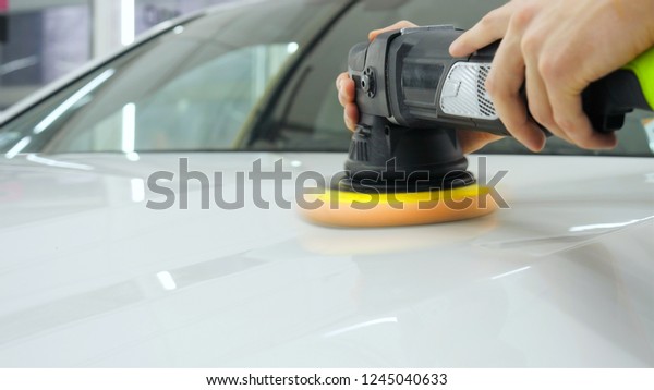 Closely shown as a\
professional worker polishes the transport (car) body using a\
polishing tool (machine). Concept from: Auto service, Car Painting,\
Machine washing.