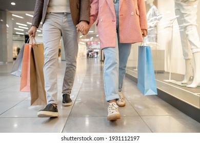 Cierre de una pareja joven que se toma de la mano y camina juntos en un centro comercial con compras