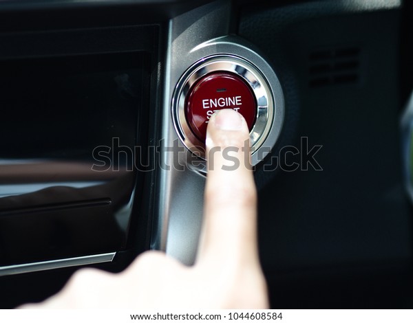 Closer human finger push\
start button of smart car red color with black and silver interior\
the car