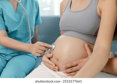 Closes up of female doctor using stethoscope to examine pregnant woman. Medical nurse puts stethoscope on pregnant mother belly that hugged by husband hands. Family receive checkup from medical staff.