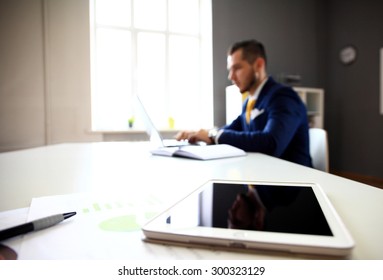 Close-shot of a tablet computer, businessman working in the background - Shutterstock ID 300323129