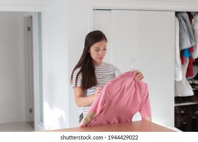 Closet Cleaning Asian Woman Organizing Her Home Donating Old Clothes To Charity Or Selling Second Hand Jacket Online On Shopping App. Girl Inspecting Fashion Pink Blazer To Donate.