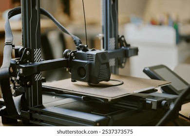 Close-up of a 3D printer during operation in a workshop setting creating an object with detailed components visible and equipment in the background.