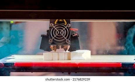 Close-up of 3d printer in process of creating some white shape figure. Thirt-dimensional printer in action.