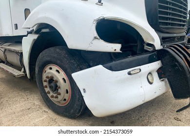 Closeup of abandoned crashed lorry after road accident on a car dump, decay on the front bumper of an white truck without headlight