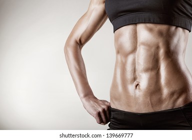 Close-up of the abdominal muscles young athlete on gray background