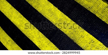 Close-up abstract background featuring bold yellow and black diagonal stripes with a rough textured surface, creating a striking industrial and geometric visual.