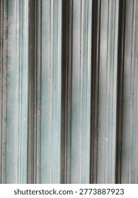 Close-up abstract background texture of vertical green metal corrugated rolling shutter door panels in natural daylight.
