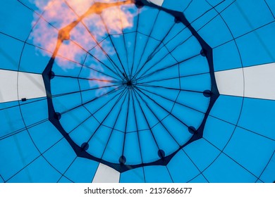 Close-up of abstract beautiful texture of geometric surface of hot air balloon, right blue colors and flame from burner. Background for bright moments of life