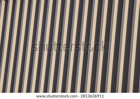 Close-up abstract image featuring diagonal stripes in beige and dark gray tones, creating a visually striking pattern with alternating light and shadow contrasts.