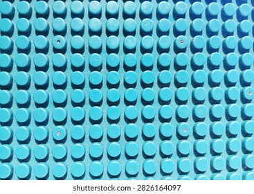 Close-up abstract pattern of a blue plastic studded building block baseplate with evenly arranged circular raised elements, creating a repetitive geometric texture and colorful background
