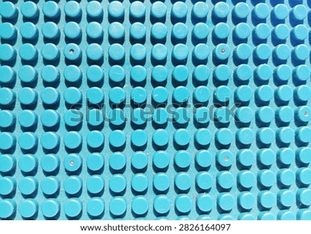 Close-up abstract pattern of a blue plastic studded building block baseplate with evenly arranged circular raised elements, creating a repetitive geometric texture and colorful background