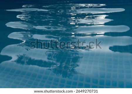 Close-up of abstract reflections and patterns on the surface of blue pool water. Ideal for backgrounds, textures, and relaxation or design themes