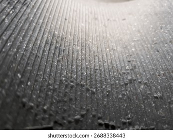 Close-up of abstract surface with vertical ridges and scattered dust particles. Ideal for texture studies, industrial design, or minimalist backgrounds.
